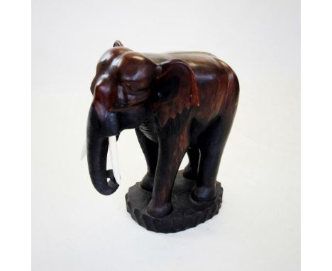 A carved hardwood model of an elephant, 20th century, modelled in a standing position and applied with composite tusks, raise