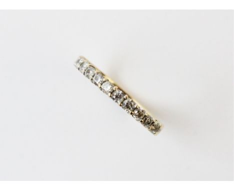 A diamond half eternity ring, comprising eleven small round brilliant cut diamonds claw set in yellow metal to a plain polish