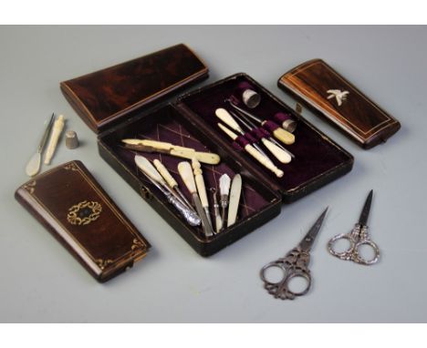 A collection of sewing implements and associated cases, to include mother of pearl handled button hooks, white metal thimbles