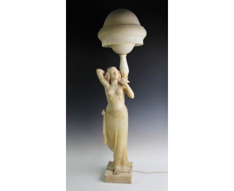 An Art Deco alabaster figural lamp, modelled as an Egyptian revival dancing girl, arms raised, below the bowl shaped shade, 1