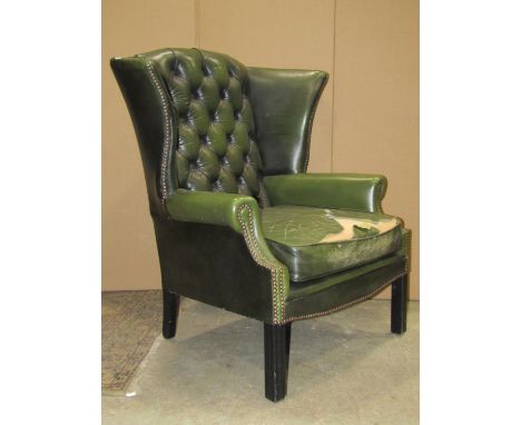 A pair of  Georgian style faux green leather wing armchairs with button backs, loose squab seat cushions and square cut and m