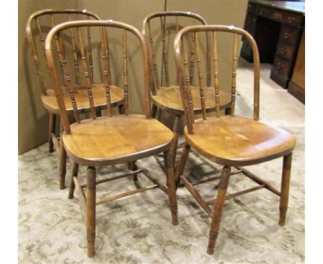 A set of four stained beechwood hoop back dining chairs with turned spindle backs over solid seats raised on splayed ring tur