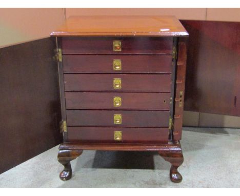 A small mahogany and stained pine table top collectors cabinet enclosed by a single door fitted with six long drawers to inte