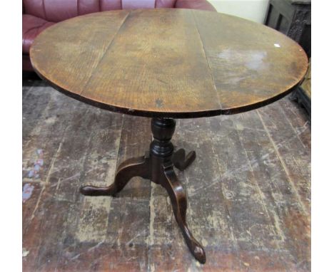 A Georgian oak snap top table the circular top 80 cm in diameter, raised on a turned pillar and shaped tripod base 