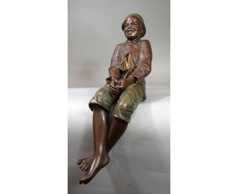 An early 20th century Austrian Goldscheider figure of a smiling bare legged boy in seated position, with impressed mark Golds