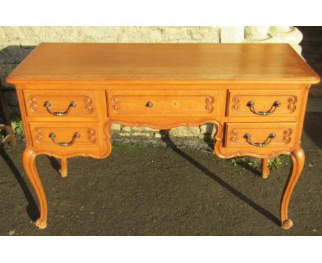 A vintage French light oak kneehole dressing table fitted with an arrangement of five frieze drawers raised on scrolled cabri