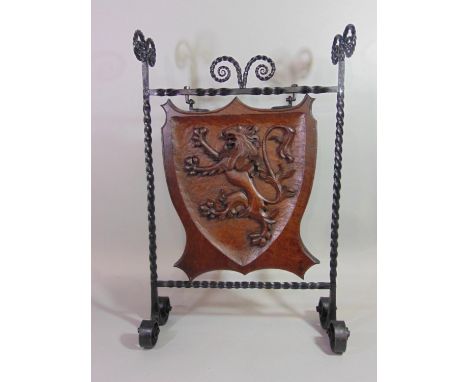 A good quality Arts &amp; Crafts style firescreen, the iron work frame with twisted and scrolled detail enclosing a carved oa