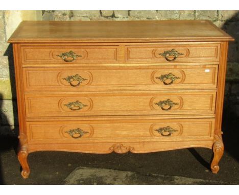 A medium to light oak commode fitted with three long and two short drawers raised on scrolled supports with acanthus detail, 