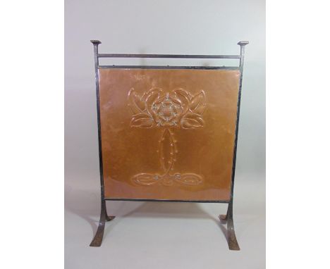 An Arts &amp; Crafts iron framed firescreen enclosing a copper panel with embossed rose design 67 cm high x 50 cm wide 