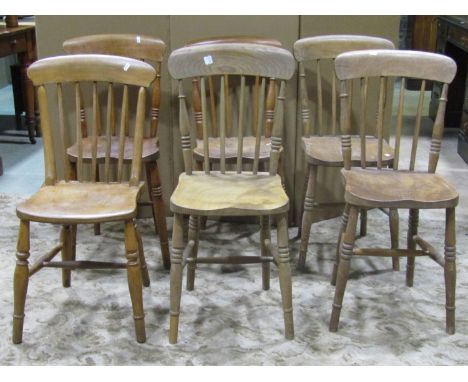 A harlequin set of six Windsor elm and beechwood stick back kitchen chairs with saddle shaped seats 