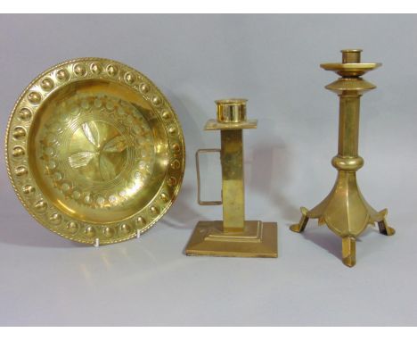 An ecclesiastical brass candle stick with hexagonal stem, one other and an embossed brass gothic style alms type dish (3) 