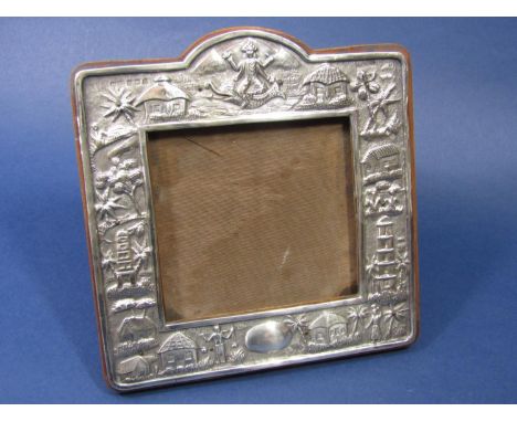 A good quality Eastern white metal easel picture frame, embossed with Buddhistic deities, village scenes, pagodas, etc, oak b