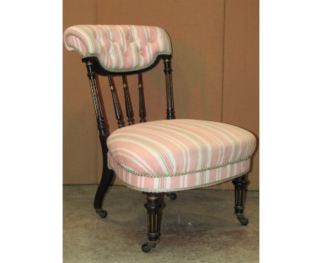 A Victorian nursing chair with gilt highlighted ebonised frame, alternating striped upholstered seat and button back 