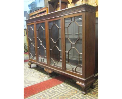 An Edwardian Chippendale revival walnut side cabinet with moulded and blind fret frieze over four astragal glazed panelled do