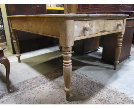 A Victorian stripped pine farmhouse kitchen table of rectangular form fitted with an end frieze drawer raised on ring turned 