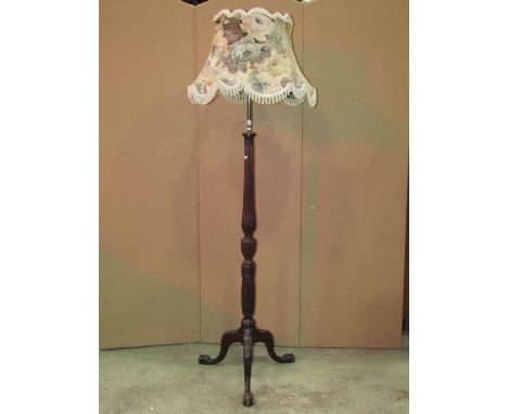 An Edwardian mahogany standard lamp in the Hepplewhite style with reeded column, wheat sheaf detail and swept tripod with cla