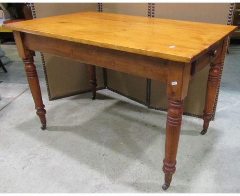 A stained pine kitchen table of rectangular form with end frieze drawer raised on ring turned and tapered supports, 122 cm lo