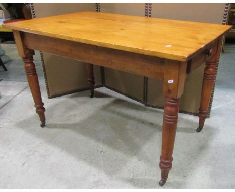 A stained pine kitchen table of rectangular form with end frieze drawer raised on ring turned and tapered supports, 122 cm lo