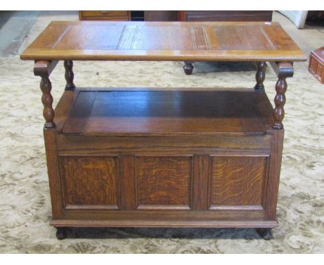 An oak monks bench with sliding rectangular panelled top raised on turned bobbin supports over a hinged box base with panelle