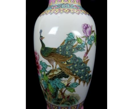 A Chinese porcelain famille rose vase decorated with a peacock amid peony blossoms beneath a border of scrolling peonies, red