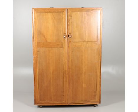 ERCOL ELM DOUBLE WARDROBE. An elm two door wardrobe with hanging rail, supported on roller casters. Manufacturer's label to d