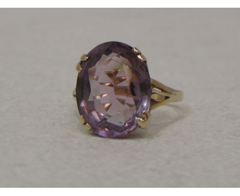 A lady's dress ring having an oval amethyst stone in a four claw set mount on a yellow metal loop, no marks, tested as 18ct g