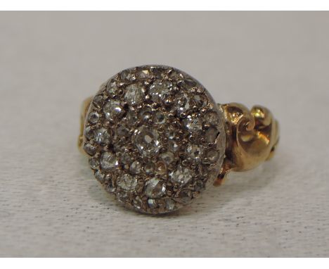 A lady's dress ring having a diamond chip cluster in a pave setting to moulded shoulders on a yellow metal loop, no marks tes