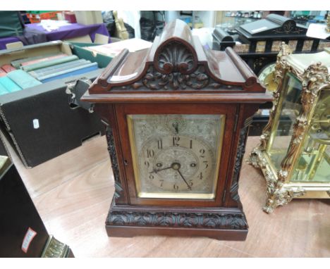 A late 19th century mahogany case mantel clock having carved foliate decoration and silvered rectangular face, engraved for T