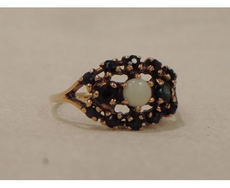 A lady's dress ring having a central opal within an oval cluster of sapphires in a claw set shaped mount on a 9ct gold loop, 