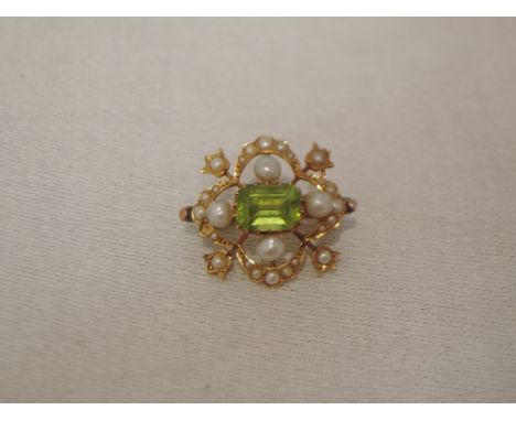 An Edwardian style yellow metal brooch having a central peridot within a seed pearl border, no marks, previously tested as 9c