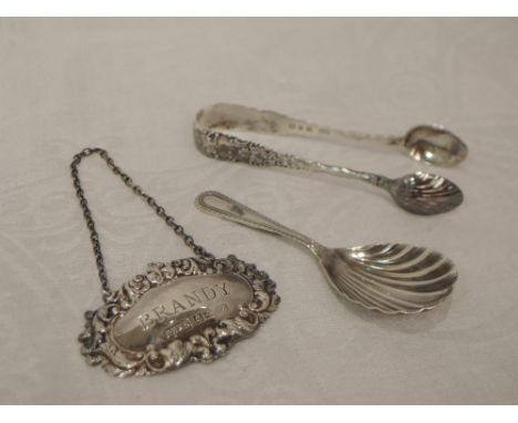 Three pieces of HM silver including a scallop shell caddy spoon, Brandy decanter label and pair of sugar nips having moulded 