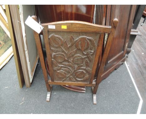 An early 20th century oak firescreen having carved panel decoration 