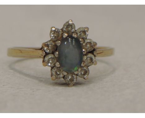 A lady's dress ring having a faux opal and cubic zirconia cluster on a 9ct gold loop,  size O