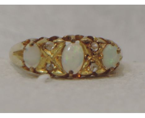 A lady's dress ring having three oval opals interspersed by two pairs of diamond chips in a gallery mount on an 18ct gold loo