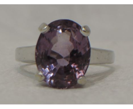 A lady's dress ring having an oval amethyst stone in a four claw raised mount on a white metal loop stamped 14K,  size M