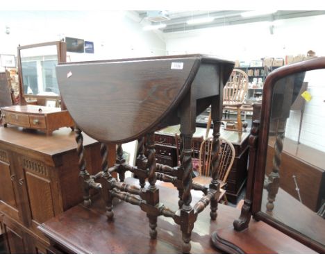 An early/mid 20th century oak occasional table having oval drop leaf top on twist gate legs