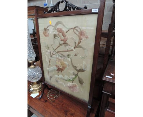An Edwardian mahogany firescreen having crewel work panel and splay supports