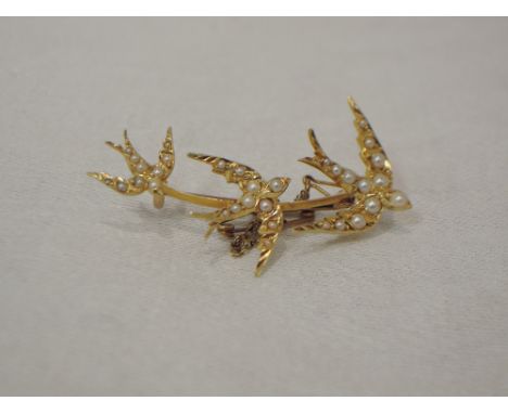 A yellow metal brooch stamped 15ct modelled as a trio of swooping swallows with seed pearl decoration and safety chainCONDTIO