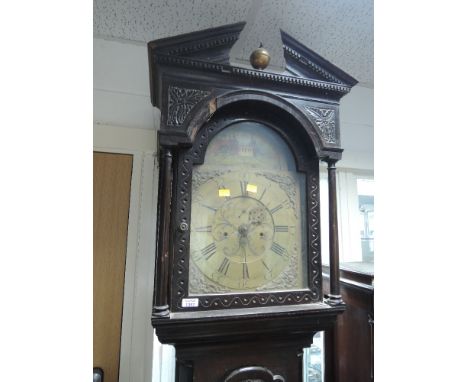 A late 18th century dark oak longcase clock having crest and carved pillar hood containing brass face with additional painted