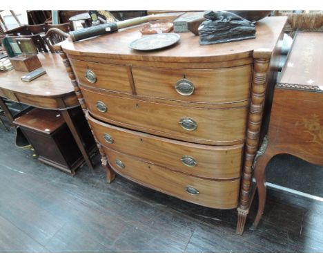 A 19th century bow front chest of two short and three long cockbeaded drawers, flanked by bobbin pillars and reeded shaped fe