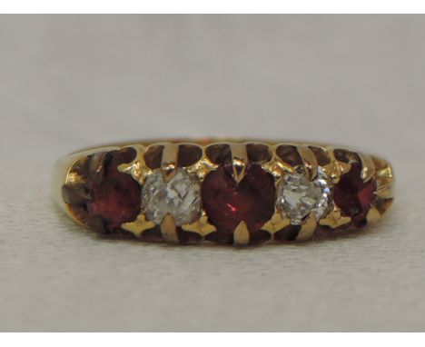 A lady's dress ring having three ruby style stones interspersed by two diamonds in a claw set gallery mount on a yellow metal