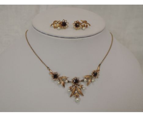 A 9ct gold necklace having central articulated garnet and seed pearl set floral panels on a fixed chain with matching stud ea