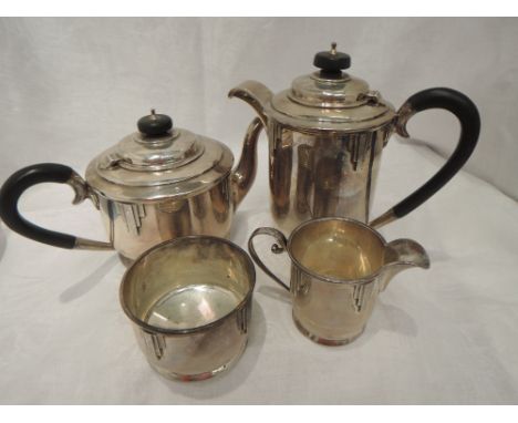 A four piece silver tea set of 1930's form having engine turned architectural detail, hard wood handles, and circular pedesta