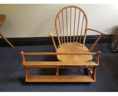 An Ercol elm rocking chair with a wall mounted plate rack.