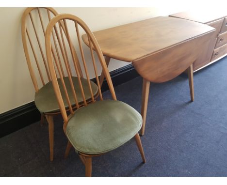 An Ercol elm drop leaf table together with four stick back dining chairs.