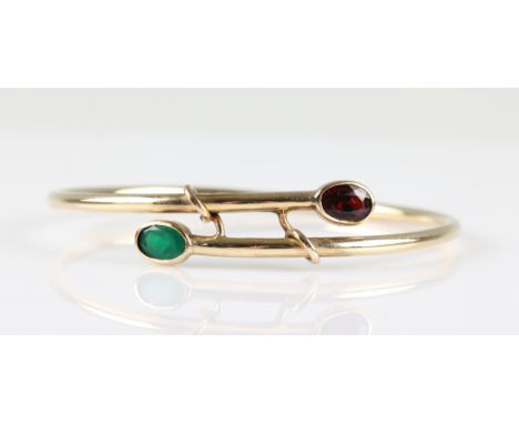 A 9ct yellow gold bangle, the cross over design set with an oval cut green agate and an oval cut garnet, hallmarked Birmingha