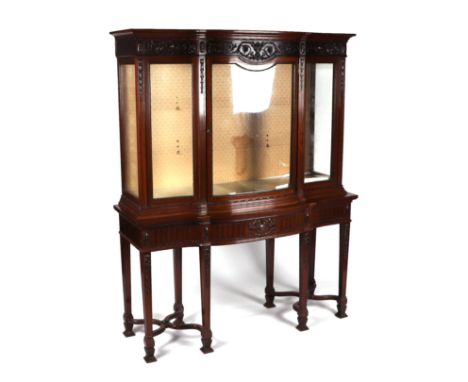 An early 20th century Chippendale Revival carved mahogany serpentine fronted display cabinet on stand, the carved frieze depi