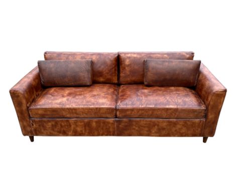 A modern design distressed brown leather three seater sofa, 206cms wide.