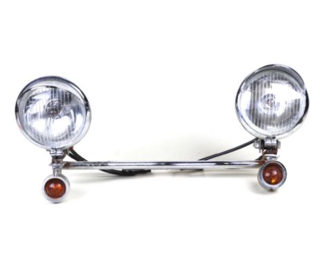 A vintage motor scooter chrome light bar with a pair of headlights and indicators.