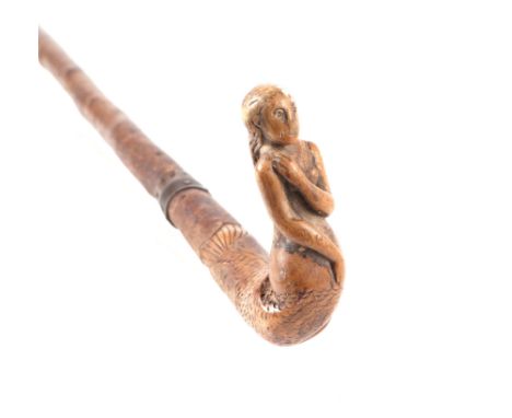 A treen walking stick, the handle carved in the form of a mermaid, 82cms long; together with a surveyor's tripod converted to